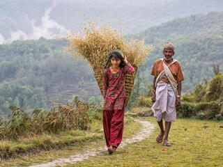 An older man and young woman walk along a path