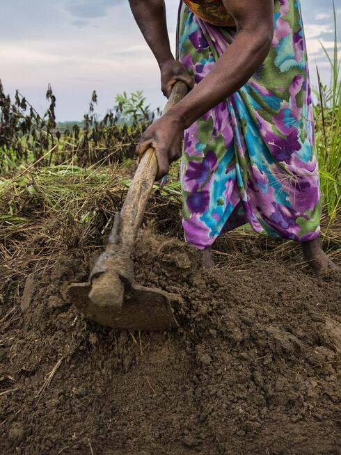 A woman from Sala Ozwa, a women’s association, helps cultivate a shared field in the village of Mbanzi.