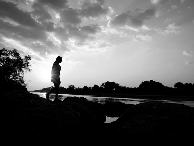 Agness Musutu, WWF's Young Expert Professional for the Freshwater Programme, walking along the edge of the Luangwa River at sunset in Mfuwe, Zambia