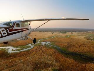 Photo of an airplane in flight over savanna landscape