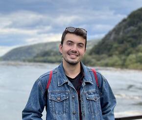 Alexander Nicolas stands in front of a lake and mountains