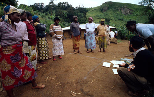 Oku women gathered outside, with lush green hills behind them. An Oku community resource mapping exercise designed to determine which tree species the women prefer to use for their firewood.