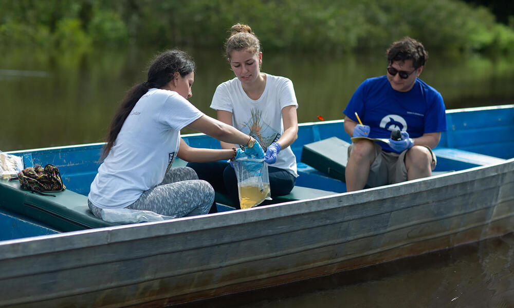 Three people in boat testing water