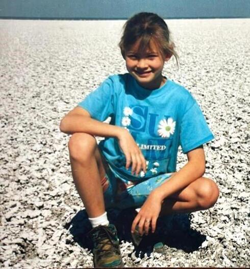 The author as a child kneels on the ground smiling in Etosha National Park