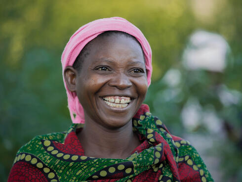 A woman smiles at the camera amidst a natural backdrop