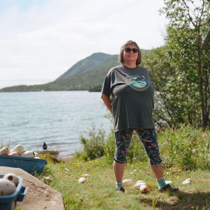 Beverly Cloud stands outside her family's smokehouse with the lake and mountains in the background