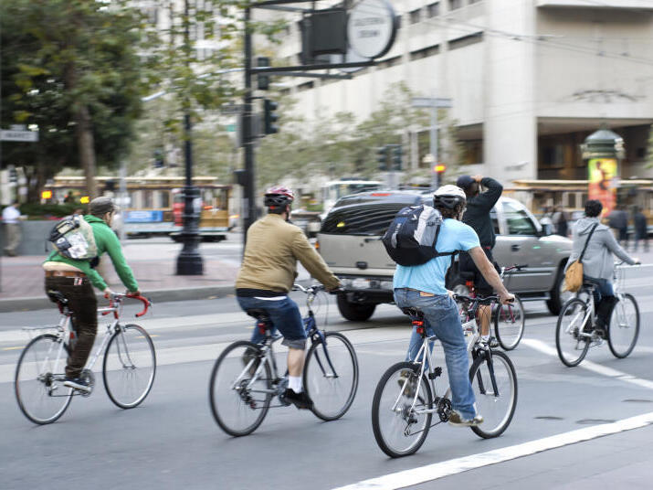 Commuters bike to work in city Environmentally conscious bikers cycling in traffic in San Francisco, California, United States