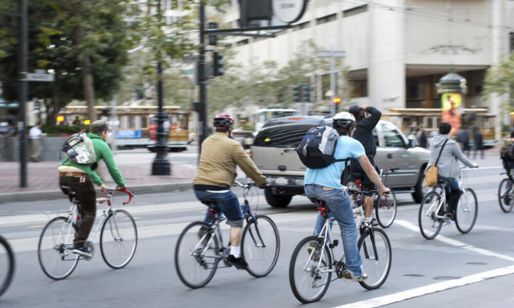 Commuters bike to work in city Environmentally conscious bikers cycling in traffic in San Francisco, California, United States