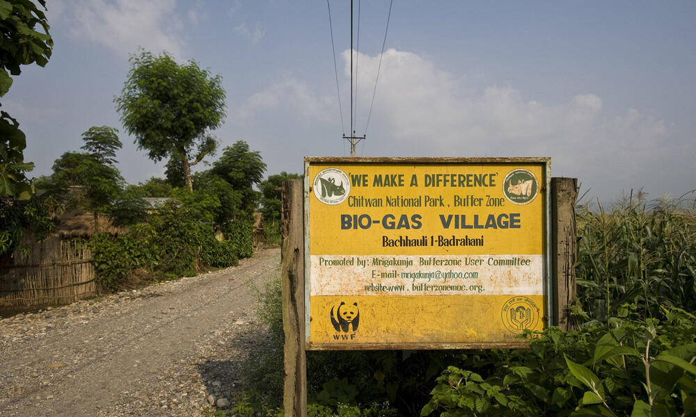 A large sign indicating the Bio-gas village in Chitwan National Park buffer zone. Nearly 90 % of the village had bio gas installed, funded by WWF. Villages used to use firewood for their cooking, but now use bio gas instead. This is not only a cleaner met
