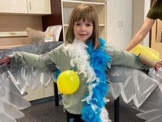 A child dresses up as a seabird wearing a bunch of feathers