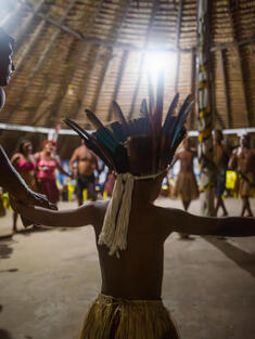 A child in traditional dress dances in circle with others
