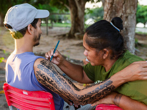 Woman paints mans arm with traditional designs