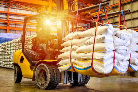 Forklift moving load of large bags in warehouse