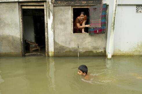 Child swimming near a flooded building
