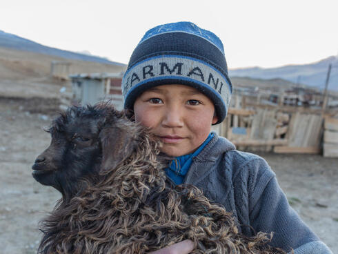 Child holding a goat in Ak-Shyrak, Kyrgyzstan