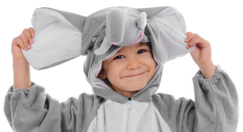 Child smiling wearing an elephant onesie and holding up the ears