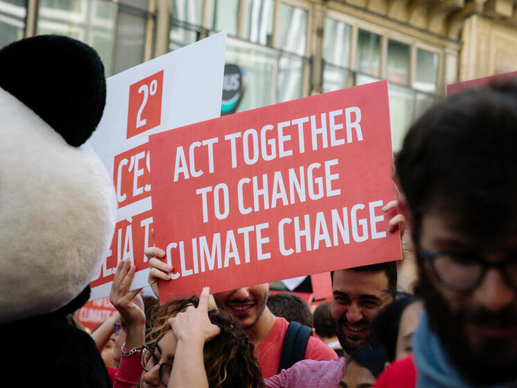 Sign reading "act together to change climate change" from the 2018 Paris Climate March