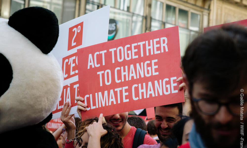 Sign reading "act together to change climate change" from the 2018 Paris Climate March