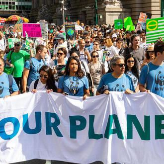 People march for climate justice carrying a sign that says save our planet.
