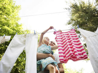 Father and daughter hang laundry outside