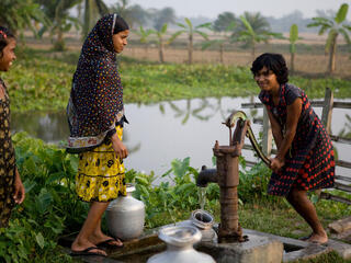 A child pumps water by hand.
