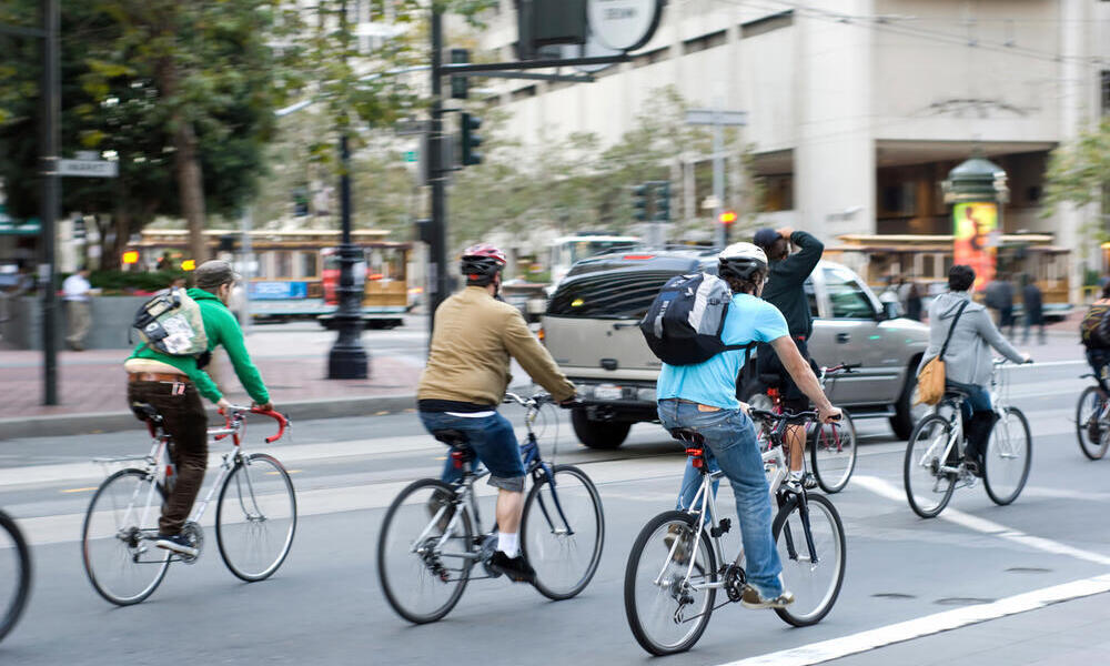 Environmentally conscious bikers cycling in traffic in San Francisco, California, United States of America.