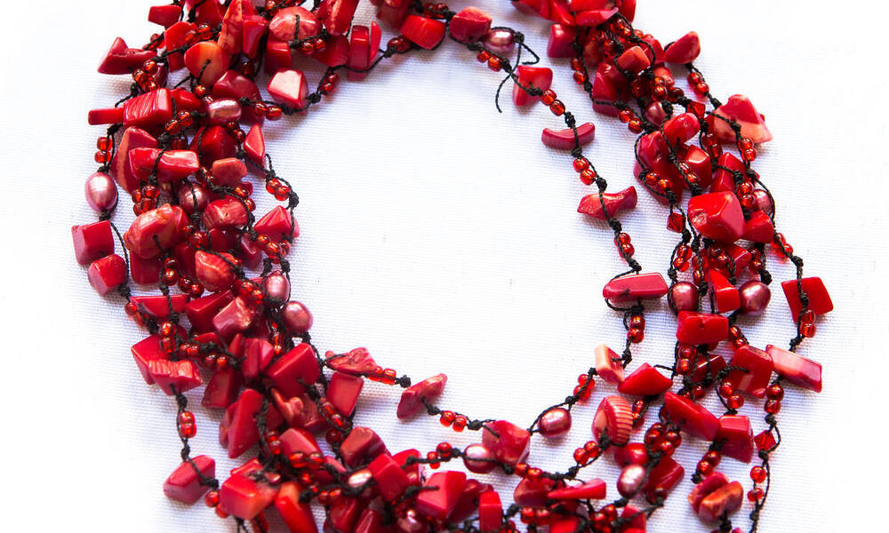 A red coral necklace with many strings and coral beads on a white background