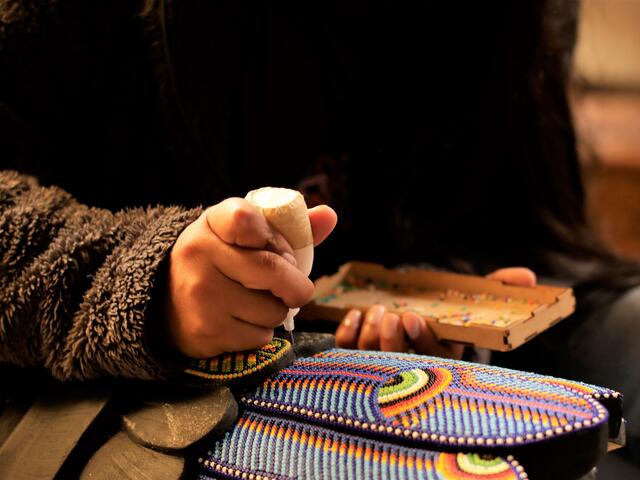 Close-up of hands beading a multi-colored mask