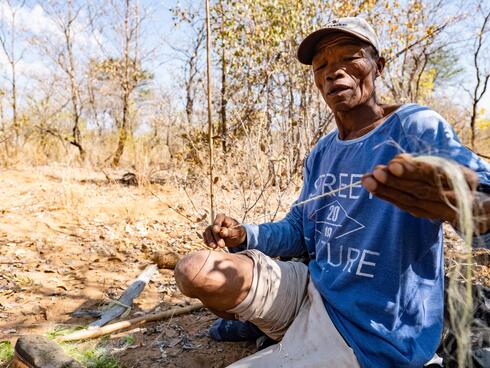 Village resident Cwi G/qao demonstrates medicinal and other plant uses on walk with visitors