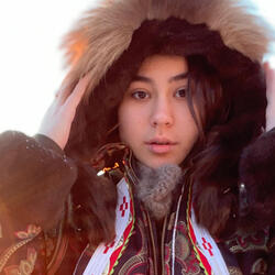 Allie Ivanoff looks straight at the camera in a large parka in the snow