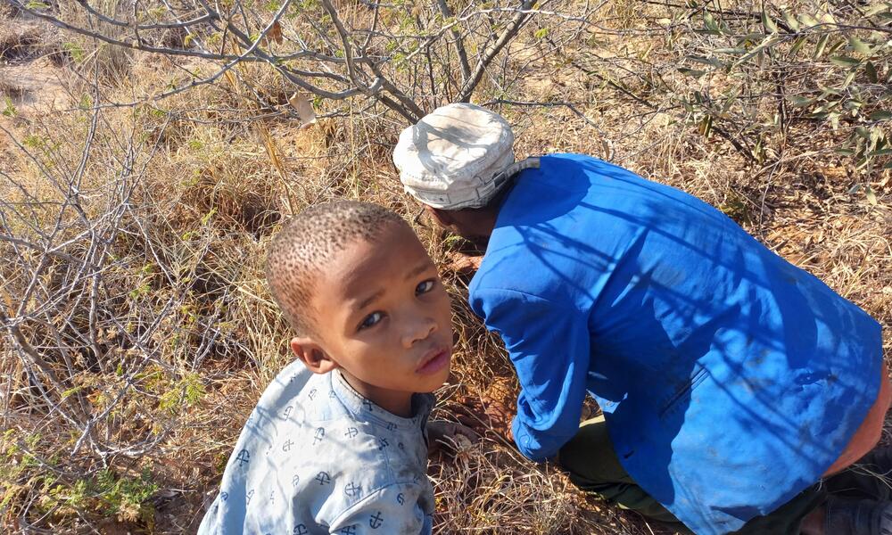 a young child looks up as his mother tends to a plant in Nams Pan Village