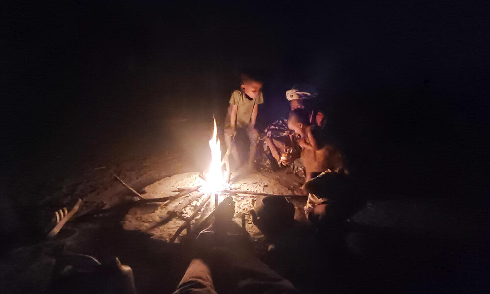 A woman and two small children gather by a campfire in Nama Pan Village, Namibia