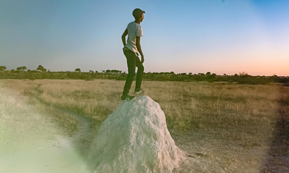 Prisms of color fall over man standing on rock in Nama Pan Village, Namibia