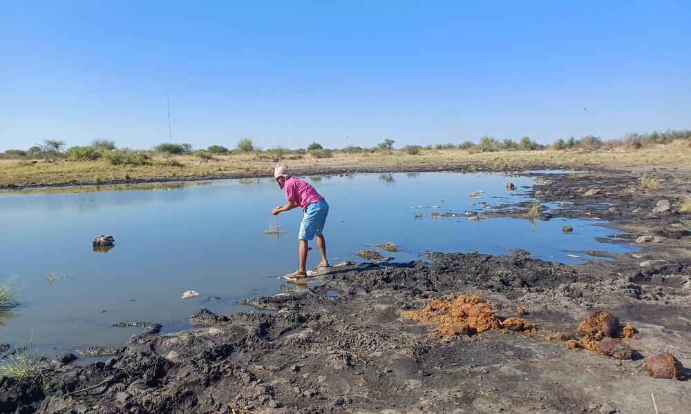 View of village woman bending to gather water