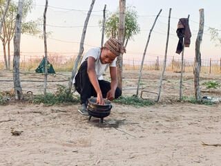 Woman tends to crops in front of fence in Nam Pan Village