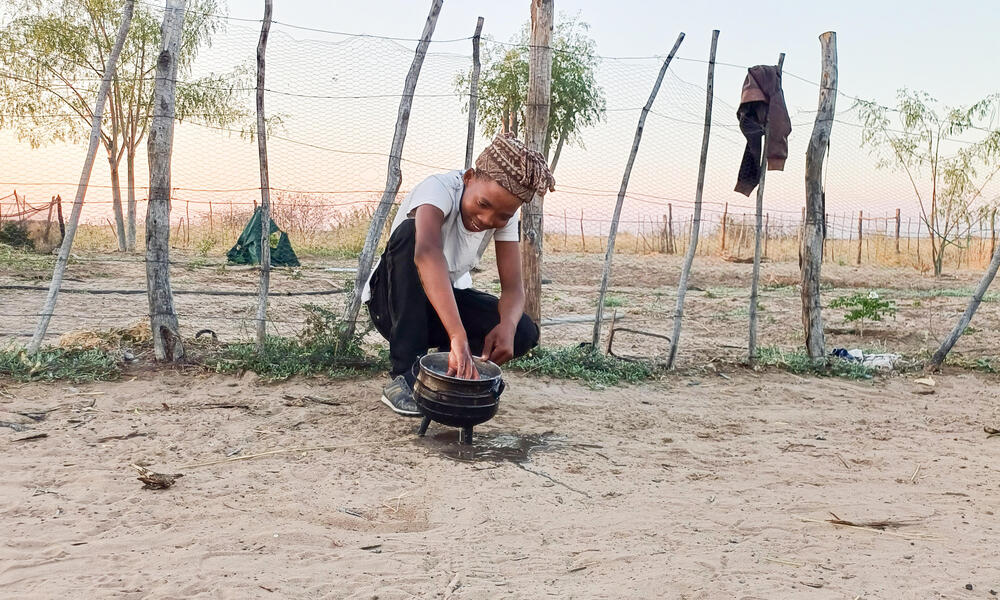 Woman tends to crops in front of fence in Nam Pan Village