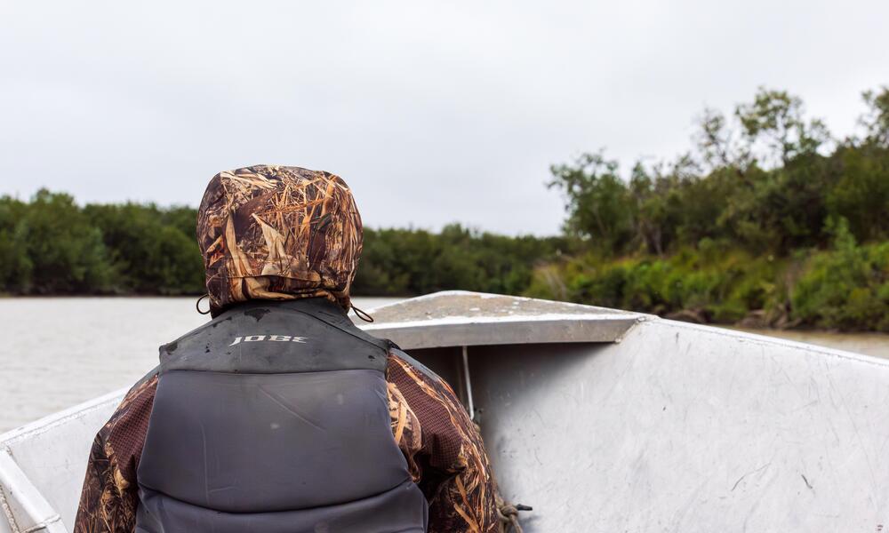 Dana Okitun, son of Marvin Okitun, looks ahead from bow of boat on Yukon River