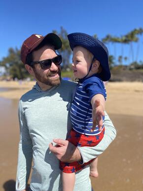 David Kuhn stands on the beach with his child