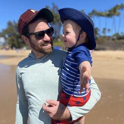 David Kuhn stands on the beach with his child