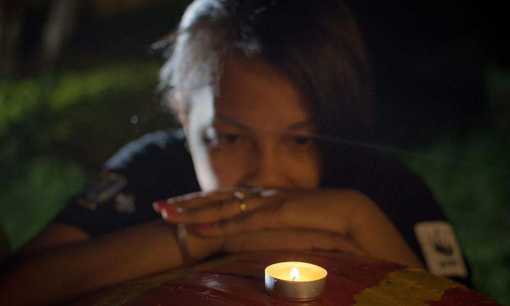 A woman reflects while looking at a candle