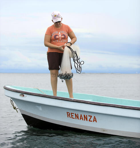 Emelly Miralda prepares to cast a net into the waters near her home