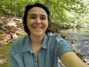 Emily Hermann with her dog in front of a river