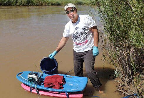Enrique in a river with measuring equipment
