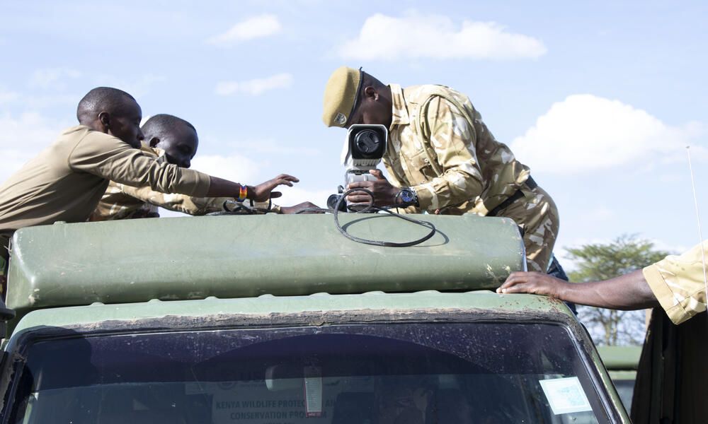 A person affixes a FLIR camera to the roof of a truck on a sunny day