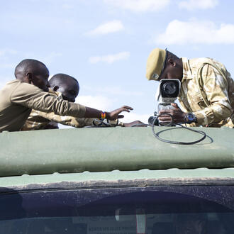 A person affixes a FLIR camera to the roof of a truck on a sunny day