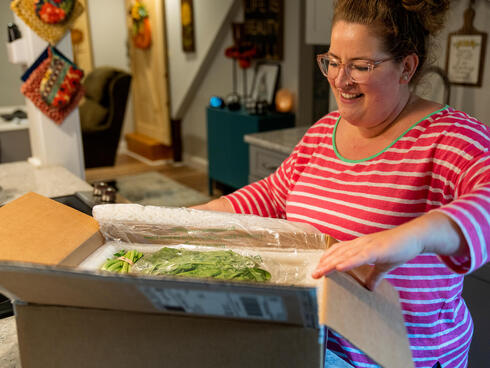 Woman opening box of vegetables