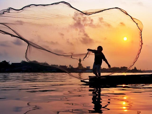 Fisher casts a line at sunset on Chaophaya River