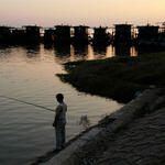 a lone fisher stands on the banks of a river