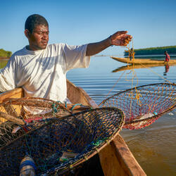 A fisherman seated in a canoe setting nets