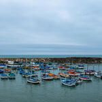 A group of small fishing boats gathers in a harbor in Peru on a cloudy day